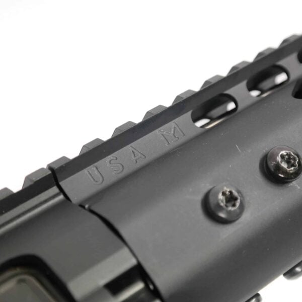 Close-up of matte black tactical firearm handguard with Picatinny slots and USA M engraving.