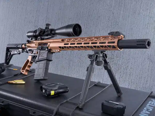 Bronze .308-cal rifle with scope and bipod on gray background.