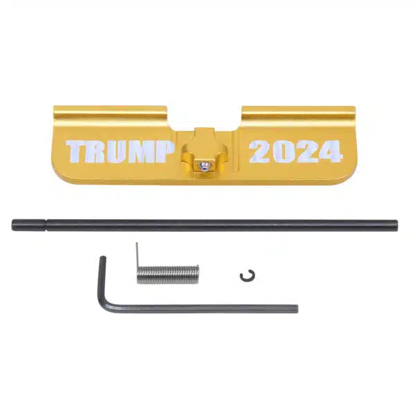 Disassembled AR-15 dust cover with TRUMP 2024 engraving on gold.